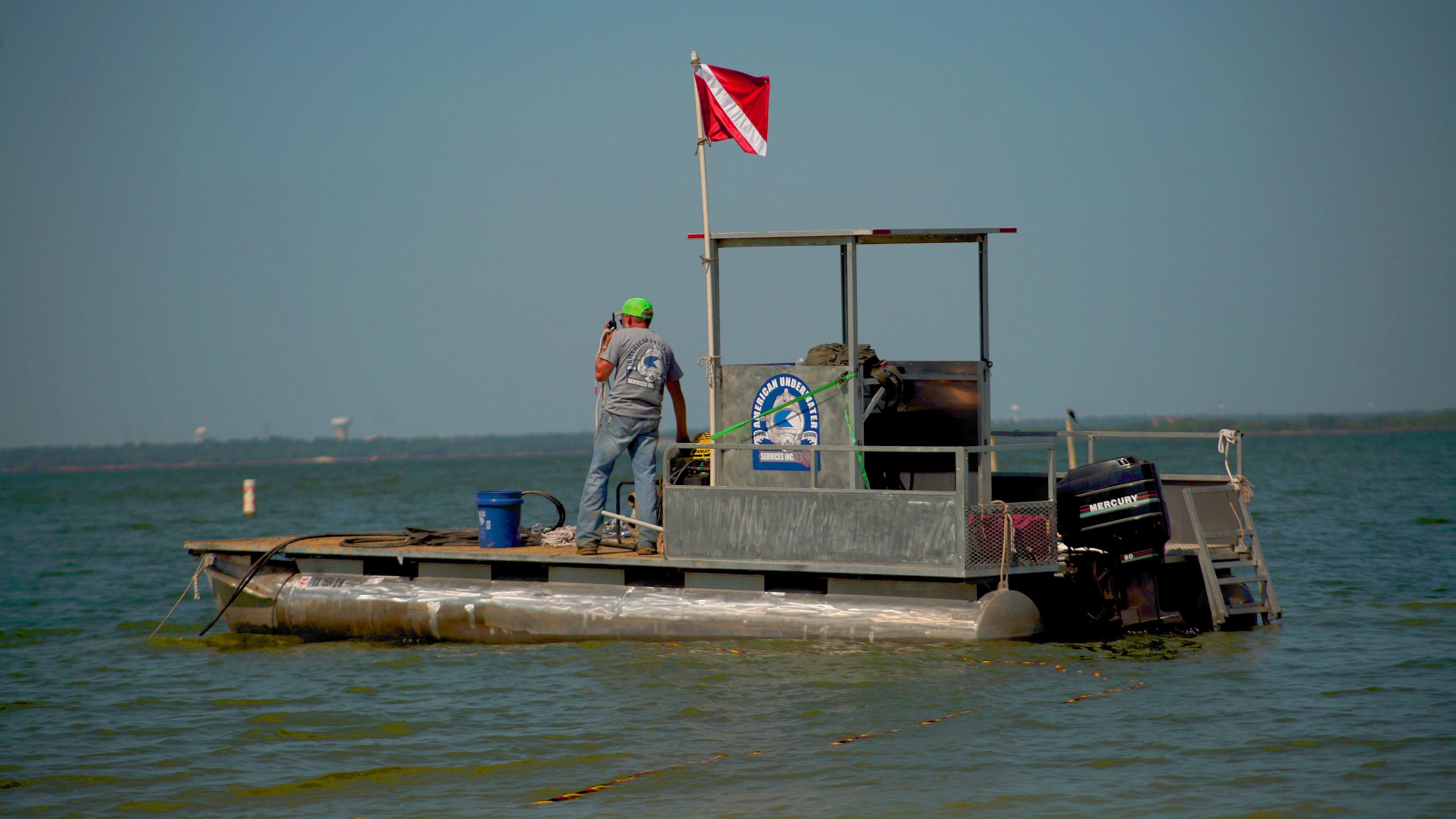 AUS Dredge & Dive commercial diving support vessel with diver down flag deployed during underwater construction operations — Texas Gulf Coast marine contractor